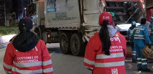 Dos mujeres gestores de convivencia cerca a un camión de basura