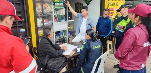 Hombres, policía y gestores del orden hablando afuera de un establecimiento.