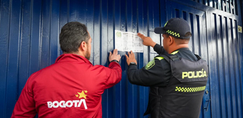 Policía y funcionario de la alcaldía sellando establecimiento comercial