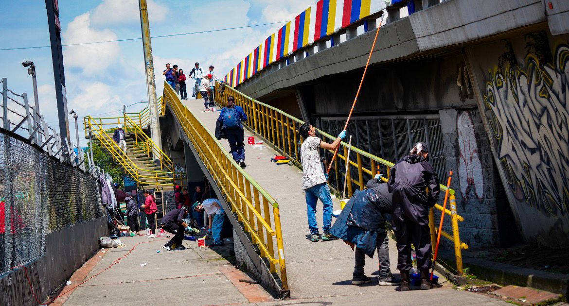 Del comparendo al mural: colados y demás infractores embellecieron puente de la calle 72 con 68 para saldar su deuda con Bogotá Varias personas pintando un puente y otra pasando sobre el