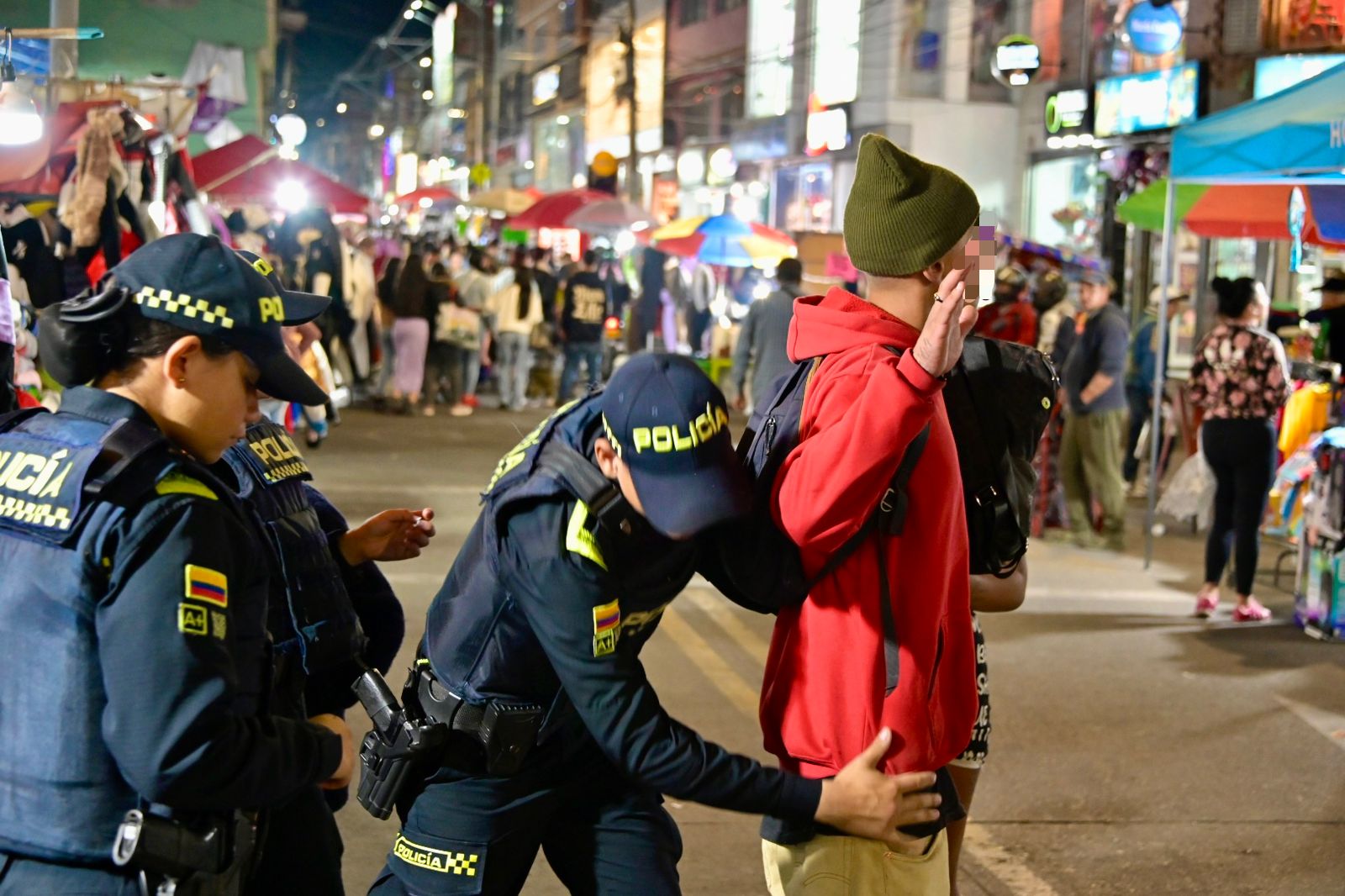 Hombre siendo requisado por varios miembros de la policía