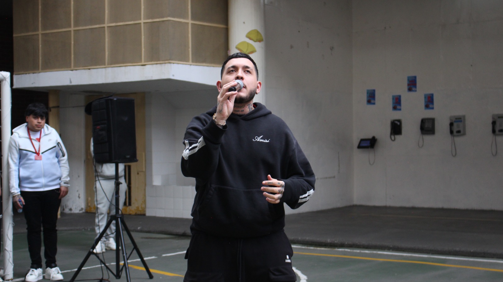 Hombre cantando con micrófono frente a varios hombres