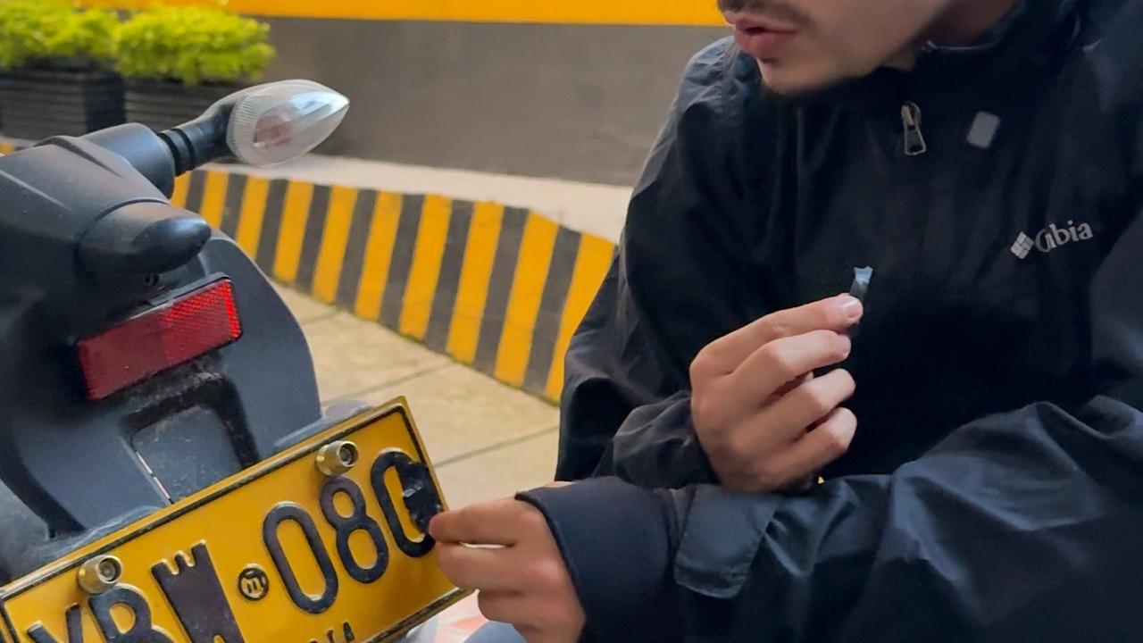 Hombre adulterando la placa de una moto