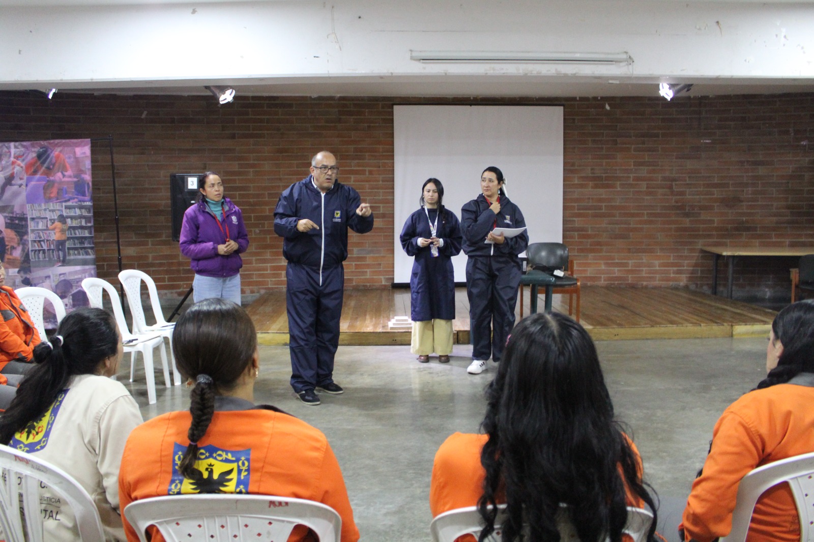 Mujeres recibiendo una charla dictada por un hombre