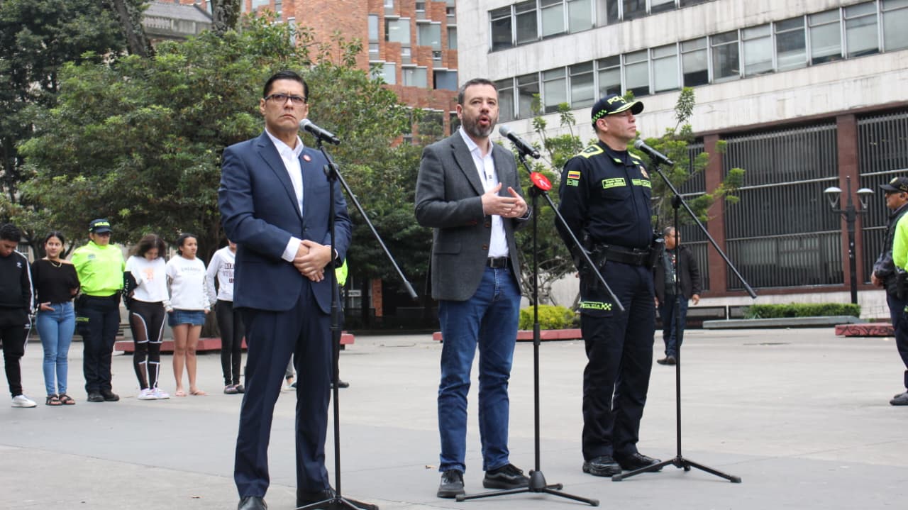 Alcalde de Bogotá dando un discurso junto con el Secretario y un policía