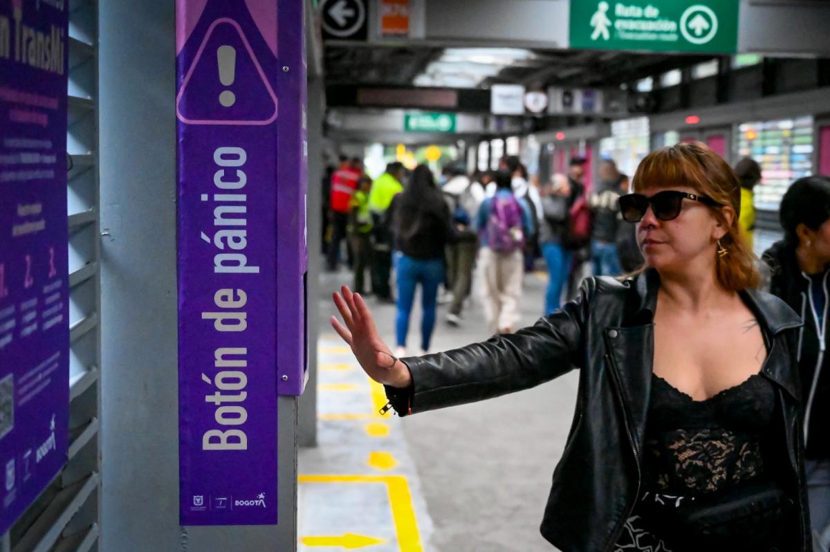 Mujer tocando el botón de pánico en estación de Transmilenio.