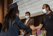 Una mujer recibiendo un grado junto a dos hombres